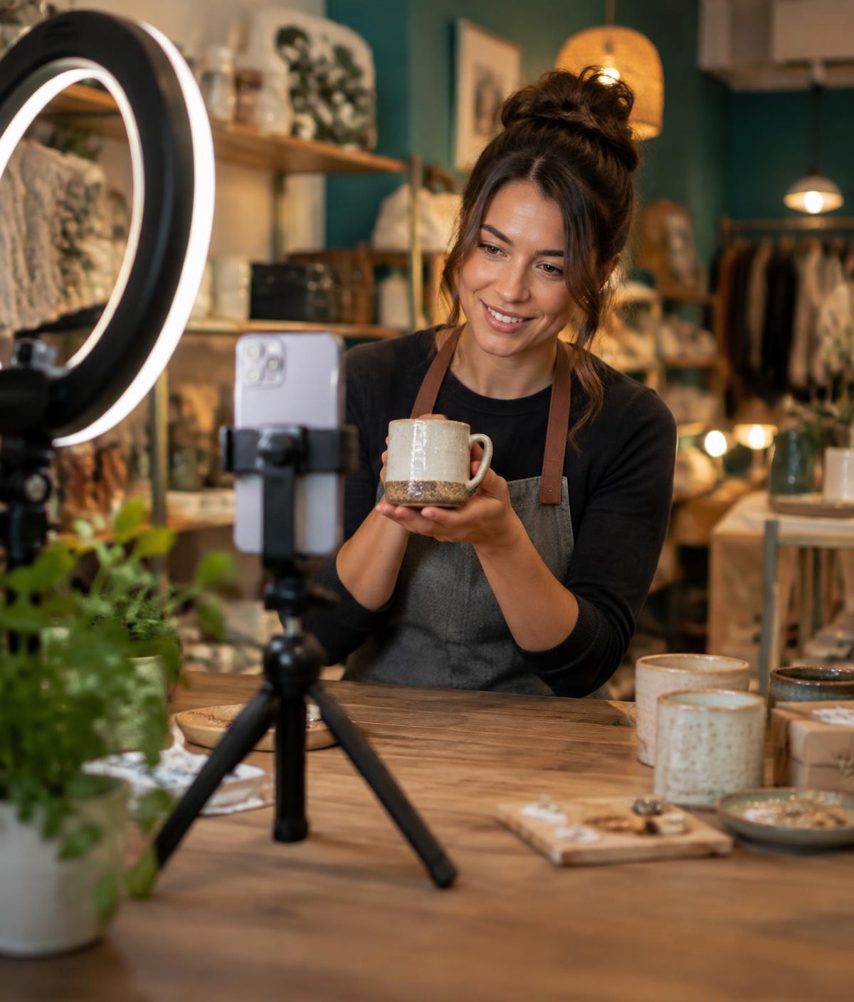 Shop owner filming a short promotional video of a product on a smartphone
